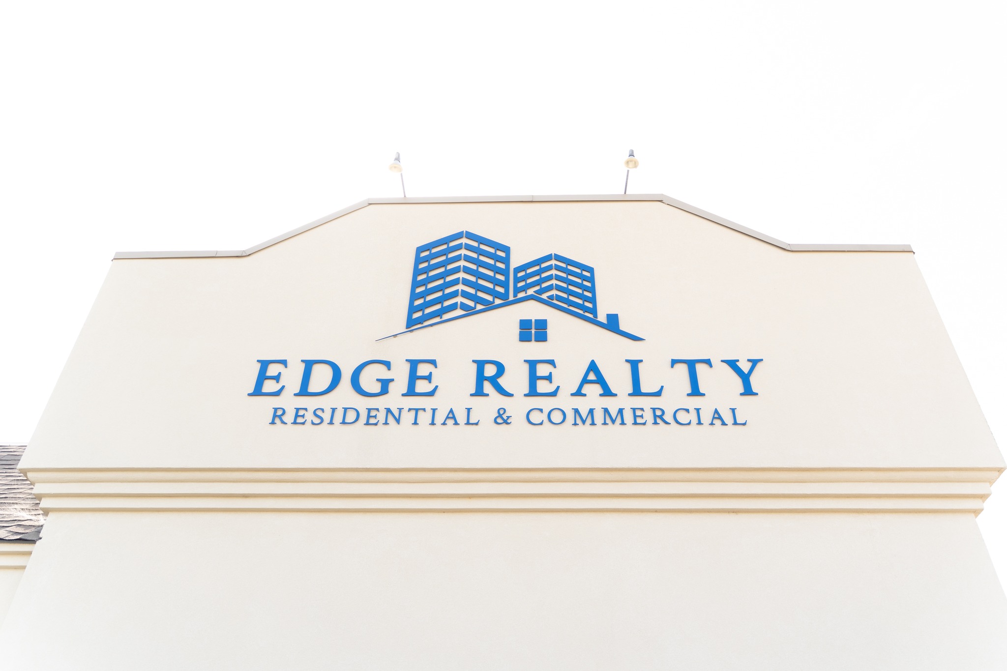 Edge Realty A building facade displays the blue logo and text Edge Realty Residential & Commercial with an icon of buildings and a house above the company name on a white background.