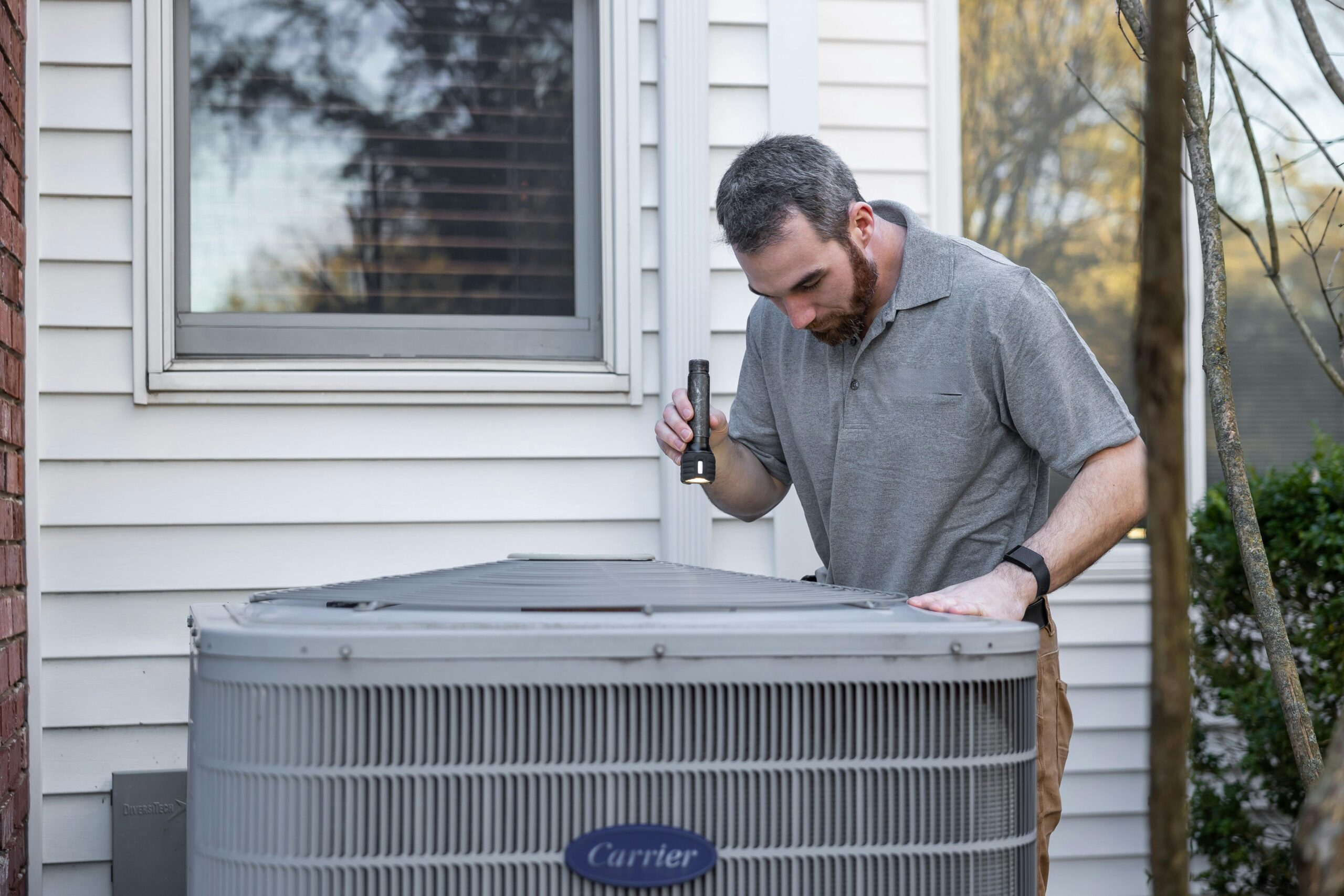 Homeowner checking HVAC unit outside a Central Arkansas home in summer